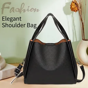 Minimalist black bucket bag in pebble leather with top handles and adjustable strap
