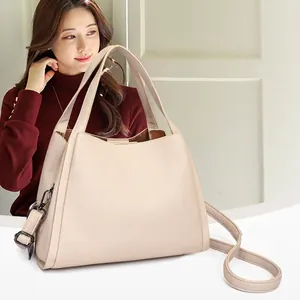 Chic cream pebbled leather tote bag with dual handles and crossbody strap on model
