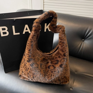 Sac bandoulière en fausse fourrure léopard avec bordure rétro sur un canapé noir