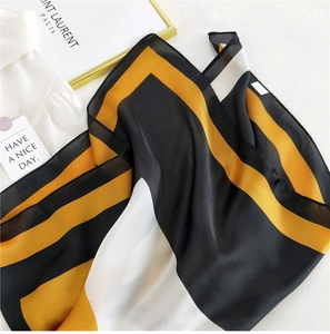 Detail view of square silk scarf with geometric color blocks in black, ginger and white