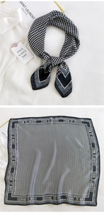 Detail of a black and white houndstooth silk scarf with elegant text and luxury styling