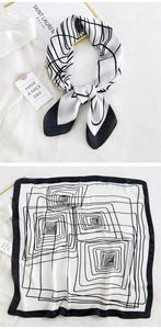 Detail of a black and white silk square scarf featuring modern geometric spiral patterns