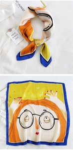 Detail of square silk scarf showing vibrant cartoon girl illustration and satin texture