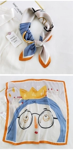 Detail of a square silk scarf with cartoon queen print and orange border on white shirt