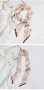 Detail of pink floral silk scarf with white blossoms and dark brown rolled edges