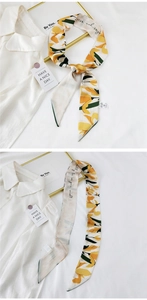 Detailed view of floral long silk scarf with yellow flowers on a white shirt