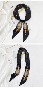 Detail of a black twilly silk scarf with gold celestial patterns and Fashionable text