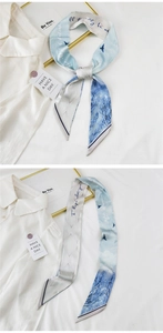 Detail of light blue and beige silk scarf with bird prints and elegant artistic patterns
