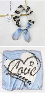 Detail of a blue and white square silk scarf with a Love heart print and smooth texture