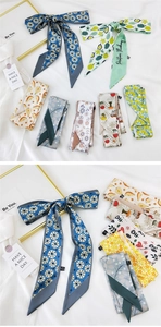 Close-up of assorted floral and geometric print skinny silk scarves on white fabric