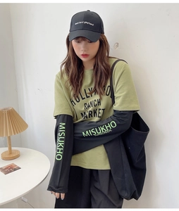 Detail of neon green logo print on the black sleeve of a casual layered t-shirt