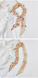 Detail of raspberry print narrow silk scarf with Positive Thinking embroidery on white fabric
