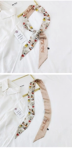 Detail of floral silk scarf with Positive Thinking text tied on a white shirt