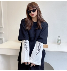 Close-up of MISUKHO SUNSCREEN printed white sleeve on a black oversized sun-protective top