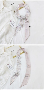 Detail of pink silk scarf showing floral patterns and elegant white letter embroidery