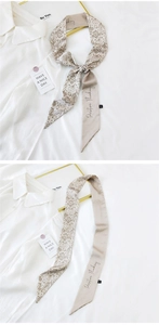 Detailed view of botanical print silk twilly scarf tied on a white collared shirt