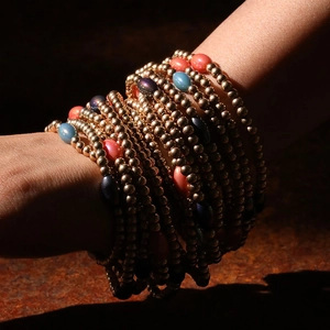 Detailed view of bohemian stacked beaded bracelets with gold beads and colorful accents