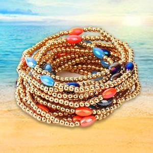 Detail of bohemian gold beaded bracelets with blue and orange accent stones