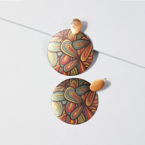 Détail de boucles d'oreilles rondes à motif tourbillon abstrait et clous dorés