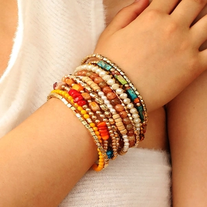 Detail of 12-piece Bohemian stone bracelet set with gold beads and turquoise on wrist