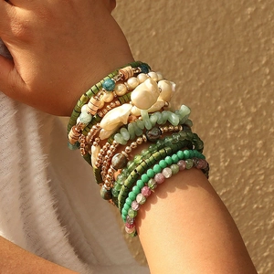 Détail de bracelets bohèmes superposés avec perles et pierres naturelles vertes
