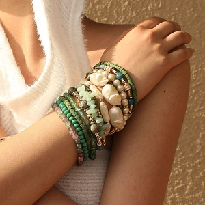 Détail de bracelets bohèmes multicouches avec perles vertes et fausses perles