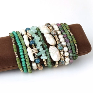 Détail d'un ensemble de bracelets bohèmes faits main avec perles nacrées sur coussin