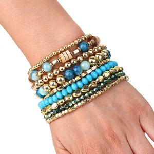 Detail of bohemian multilayer beaded bracelet set featuring blue stones and gold metal beads