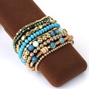Close-up of bohemian blue beaded bracelet set with gold metal beads on brown suede display