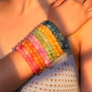 Close-up of colorful cracked glass bead bracelets worn by a model in warm sunset lighting