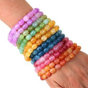 Close-up of stacked colorful cracked glass bead bracelets worn on a wrist in bright light