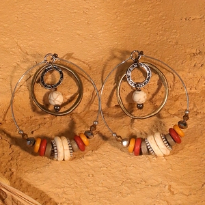 Detail of ethnic hoop earrings with marble beads and hammered metal rings in bohemian style
