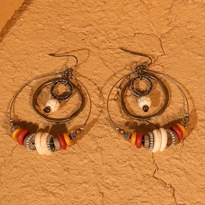 Detail view of Bohemian hoop earrings with colorful beads on a rustic textured backdrop