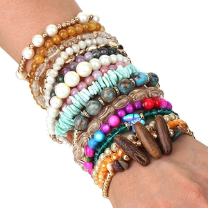 Detail of 16-piece bohemian stretch beaded bracelet set stacked on a female wrist