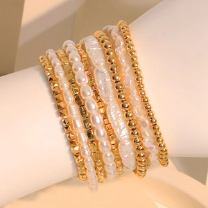 Stacked layered bracelet set with oval faux pearls and golden beads on a wrist