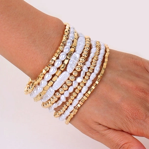 Close-up of layered bracelet set featuring imitation pearls and golden CCB beads