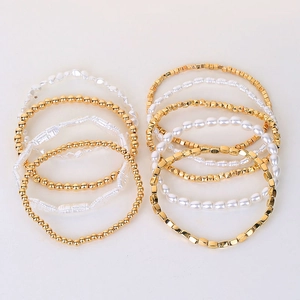Detail of beaded bracelet set with gold CCB beads and oval faux pearls in a layered style