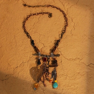 Bohemian leaf necklace with turquoise beads and wood tassels on rustic background