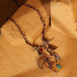 Detail of bohemian leaf pendant with turquoise and coral accents on rustic stone