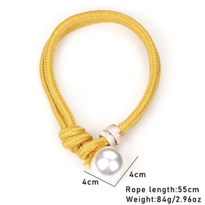 Detail showing oversized white pearl with marble beads on thick yellow braided cord