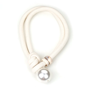 Detail of minimalist oversized pearl pendant on thick beige woven cord sweater necklace