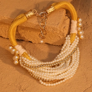 Détail d'un collier multicouche en perles d'imitation avec cordon tressé et fermoir doré