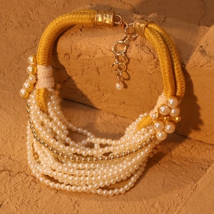 Détail du collier de perles multicouche avec cordon tressé jaune et fermoir doré