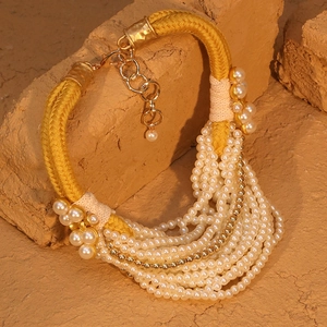 Gros plan d'un collier de perles multicouche avec corde jaune et détails dorés