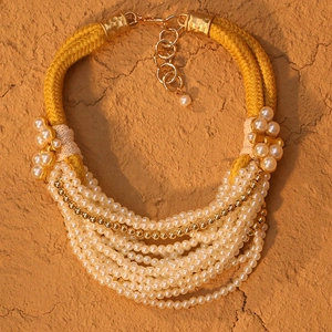 Détail d'un collier multicouche en perles avec perles dorées et cordon tressé jaune