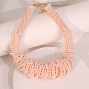 Pink chunky multi-layered beaded necklace with metal clasp on white geometric props