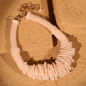 Macro shot of multi-layer pale pink beaded necklace with gold metal clasp and chain