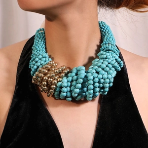 Detailed view of layered bohemian turquoise and gold bead necklace on a model