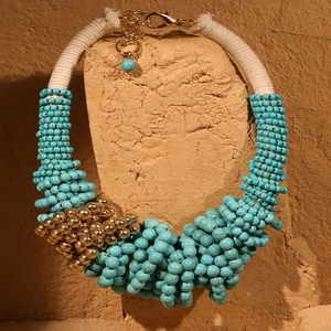 Detail of bohemian turquoise beaded necklace with gold accents and woven rope cord