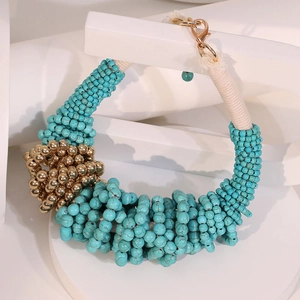 Bohemian multilayer turquoise bead necklace with gold accents on white geometric base